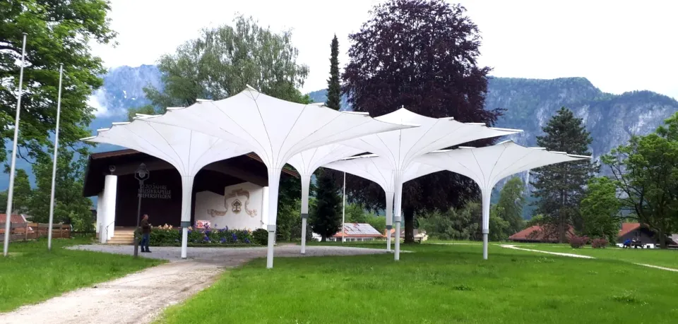 Weiße Trichterschirme in einem Park vor einem Pavillon und Bergen