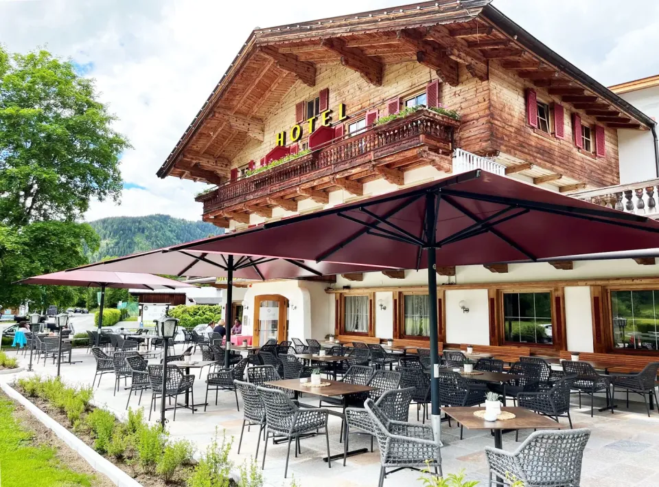 Bordeauxfarbene Großschirme vor einem Hotel mit Holzbalkon