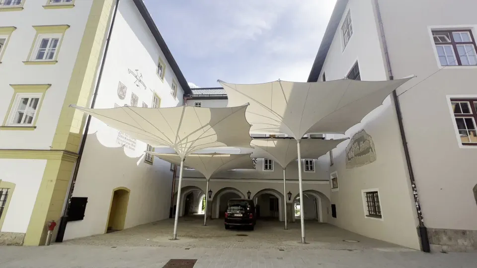 Mehrere weiße verfahrbare Trichterschirme 7 × 7 m in einem historischen Innenhof zwischen hellen Gebäuden, Projekt Kitzbühel