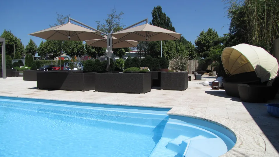 Drei Ampelschirme mit seitlichem Mast und taupefarbenen Dächern über einer Loungegruppe an einem Pool