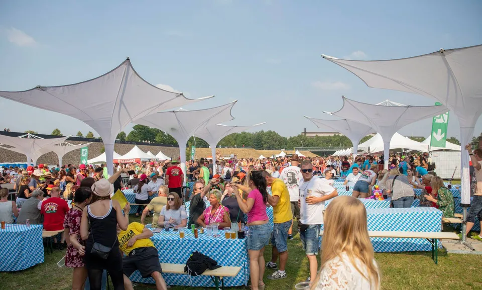 Weiße Schirme über besetzten Biertischgarnituren im Freien