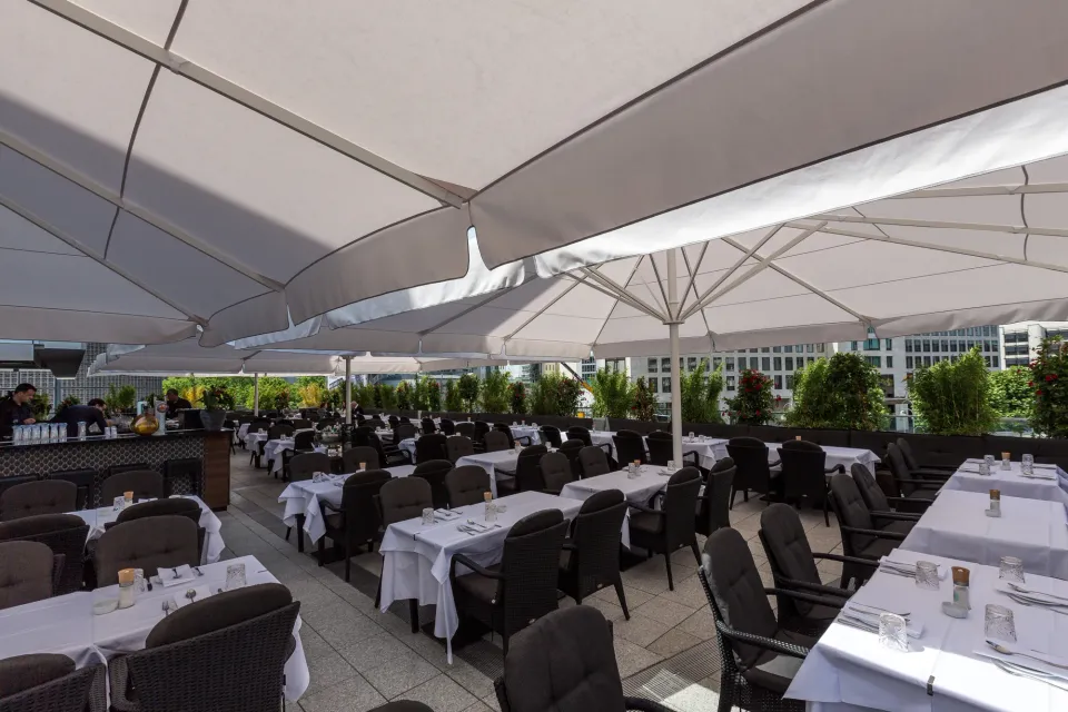 Cremefarbene Großschirme über gedeckten Tischen eines Restaurants, Blick unter die Schirmdächer