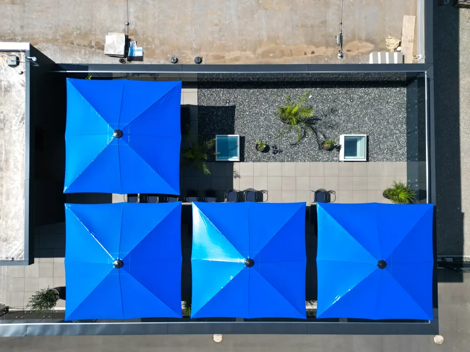 Luftbild einer Dachterrasse mit vier quadratischen blauen Schirmen nebeneinander