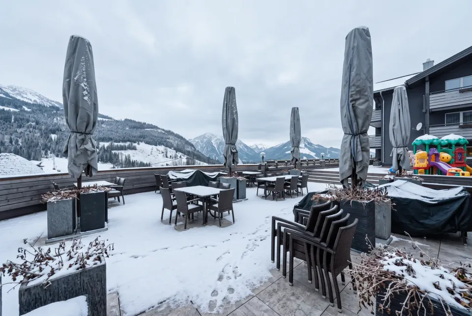Geschlossene Großschirme mit grauen Schutzhüllen auf einer winterlichen Terrasse mit Schnee