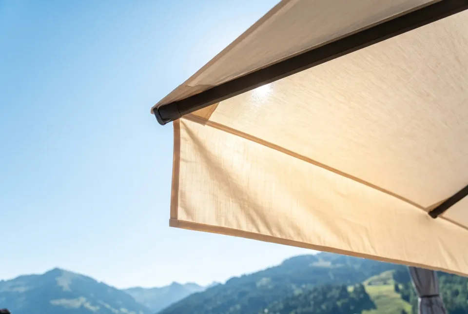 Gerader Volant am Rand eines Großschirms von unten im Gegenlicht, helles Schirmtuch